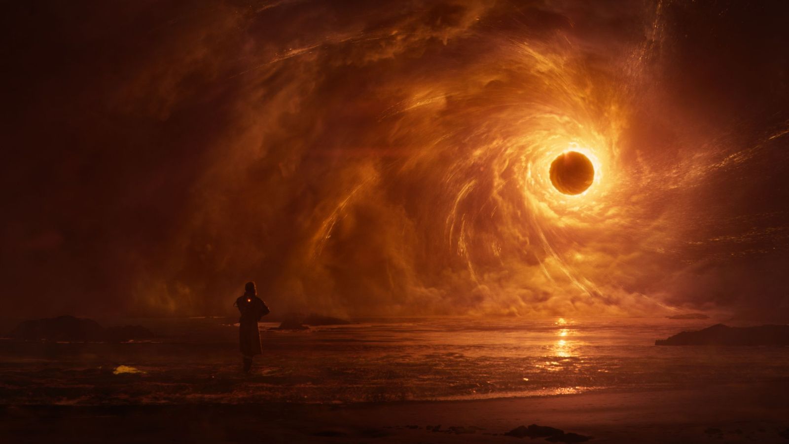 Saros trailer screenshot. A human figure in what looks like a thick coat stands in the shallows on a sand beach, lit only by the dark golden light of a total solar eclipse. The clouds seem to be drawn into a vortex by the sun. This is not how eclipses work.